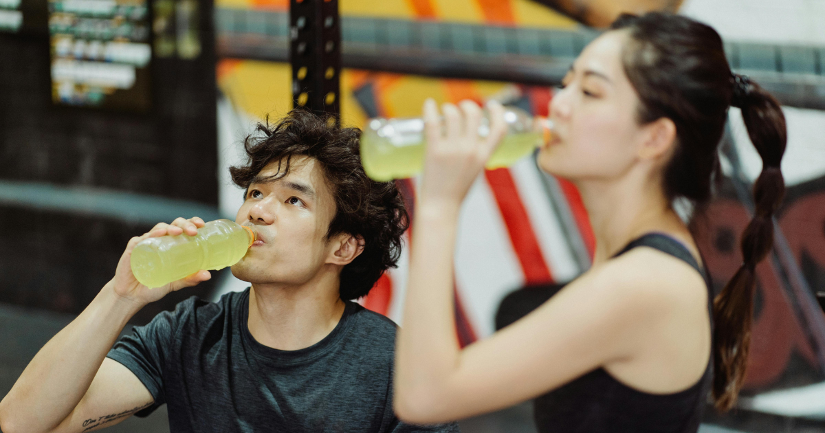 Man and woman both separately drinking from plastic beverage bottles