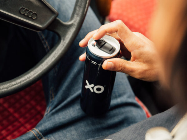 Person opening aluminum beverage can that has an XO resealable can end