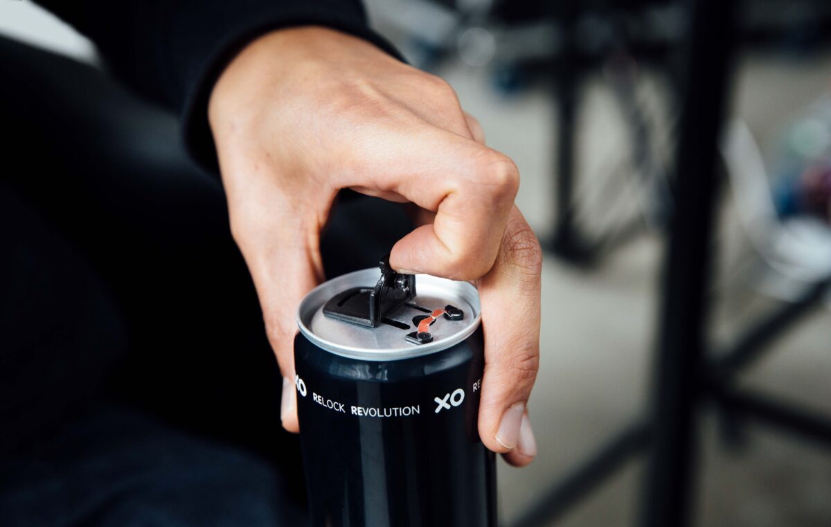 Person opening a beverage can with an XO resealable can end 