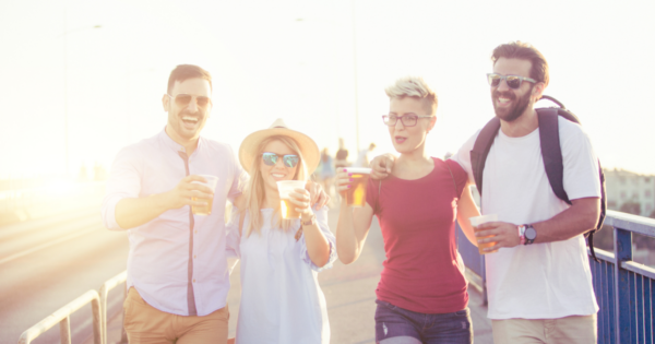 Four people walking and drinking beverages from plastic cups
