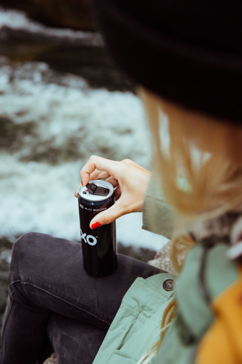 Woman opening a beverage can that has an XO resealable can end