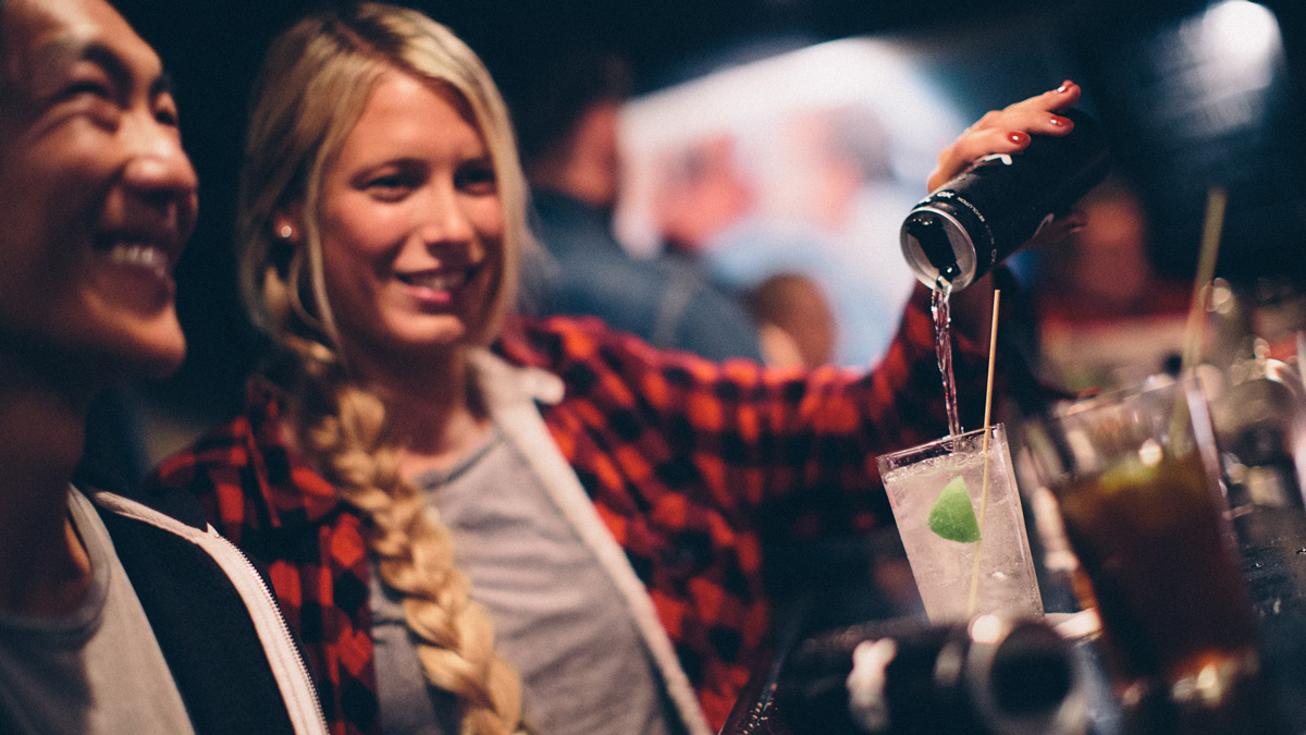 Two people enjoying a beverage being poured out of a can with an XO resealable can end